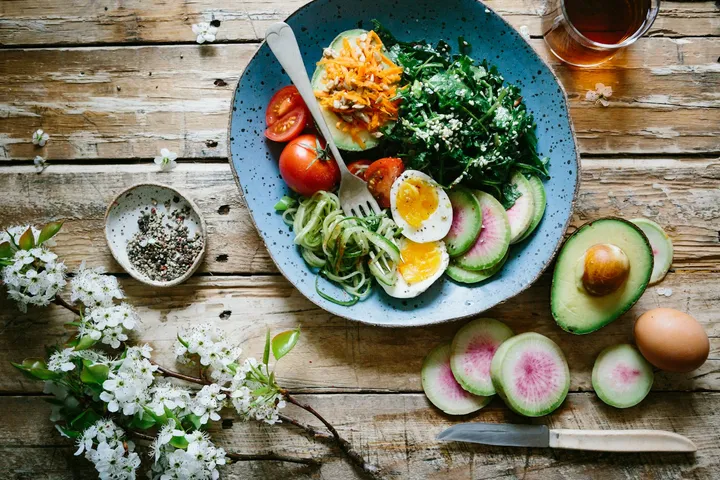 Fresh vegetables, pulses and grains arranged on a wooden kitchen counter