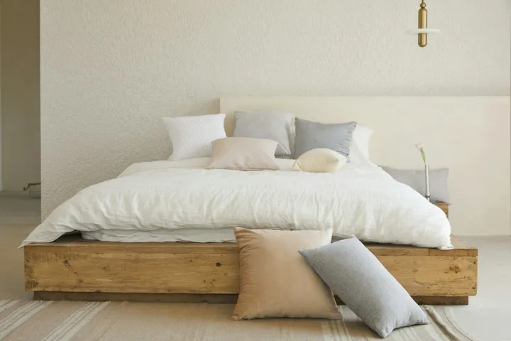 A quiet bedroom in soft early morning light with linen bedding