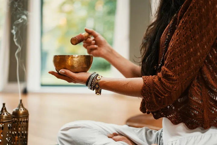 A person sitting quietly by a window with a cup of tea